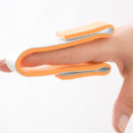 Attelle de doigt Morsa Cyberg, 30cm, en plastique rigide avec système d'ajustement. L'attelle maintient un doigt immobilisé et offre soutien, visible sur une main. Adaptée pour douleurs, entorses ou fractures légères.